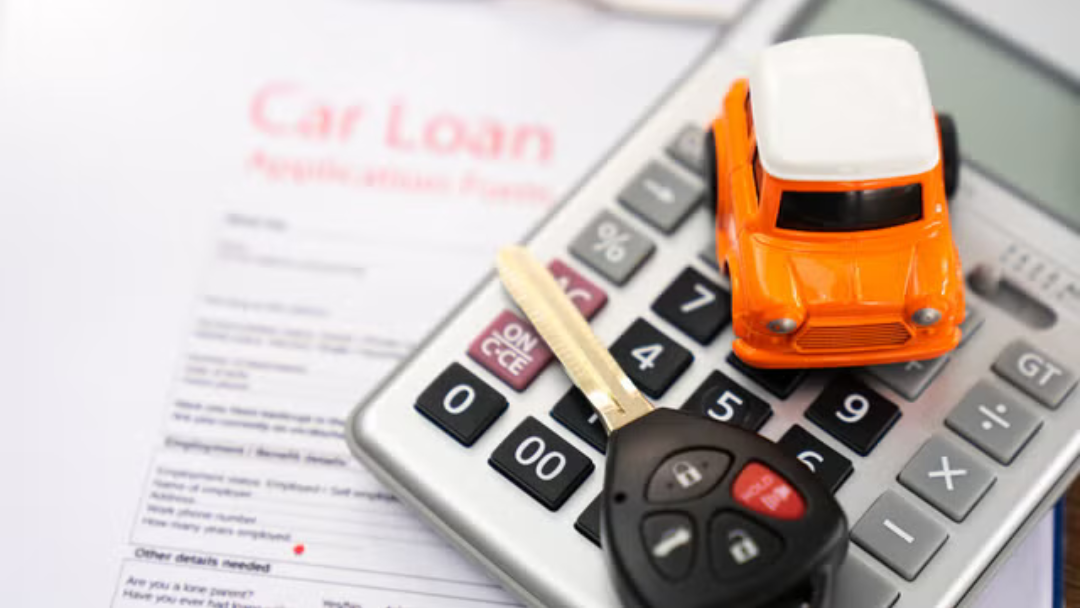 Calculator, car key, and mini toy car on top of a paper that says car loan application. financing is easy at Arnie Bauer Chevrolet GMC